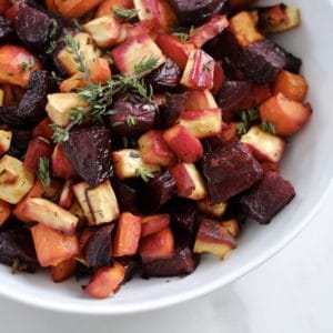 Roasted beets carrot parsnips with thyme in a white bowl.