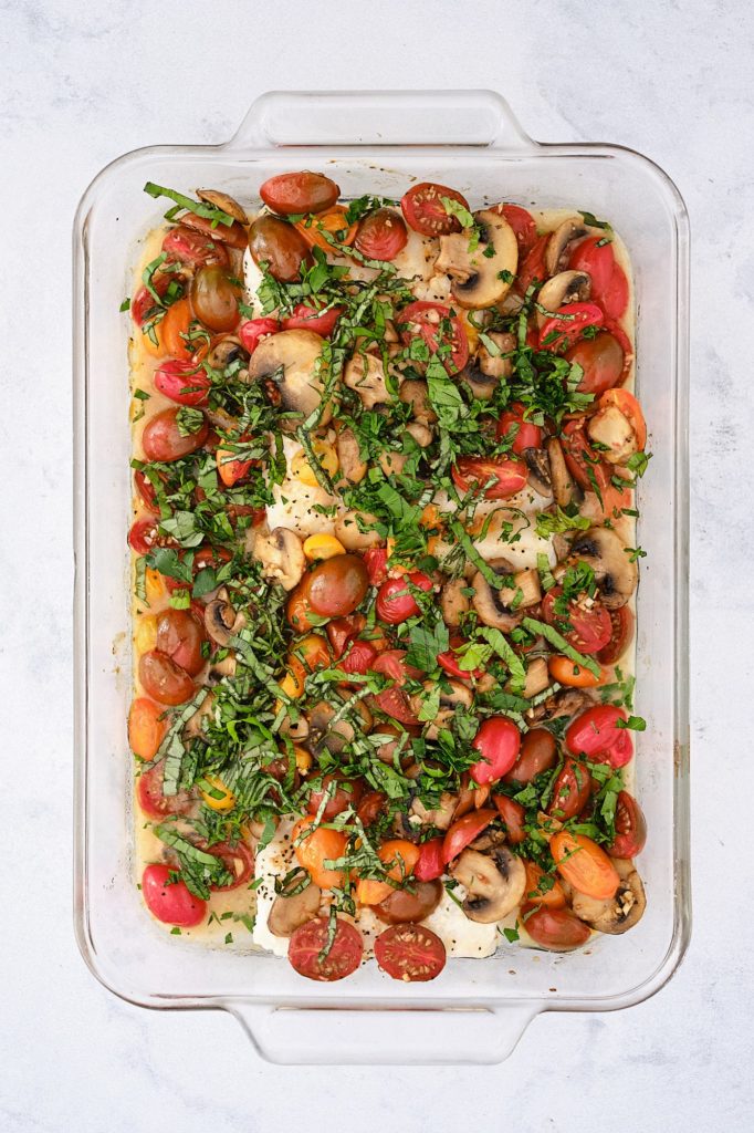 baked cod with tomatoes and mushrooms in a glass baking dish