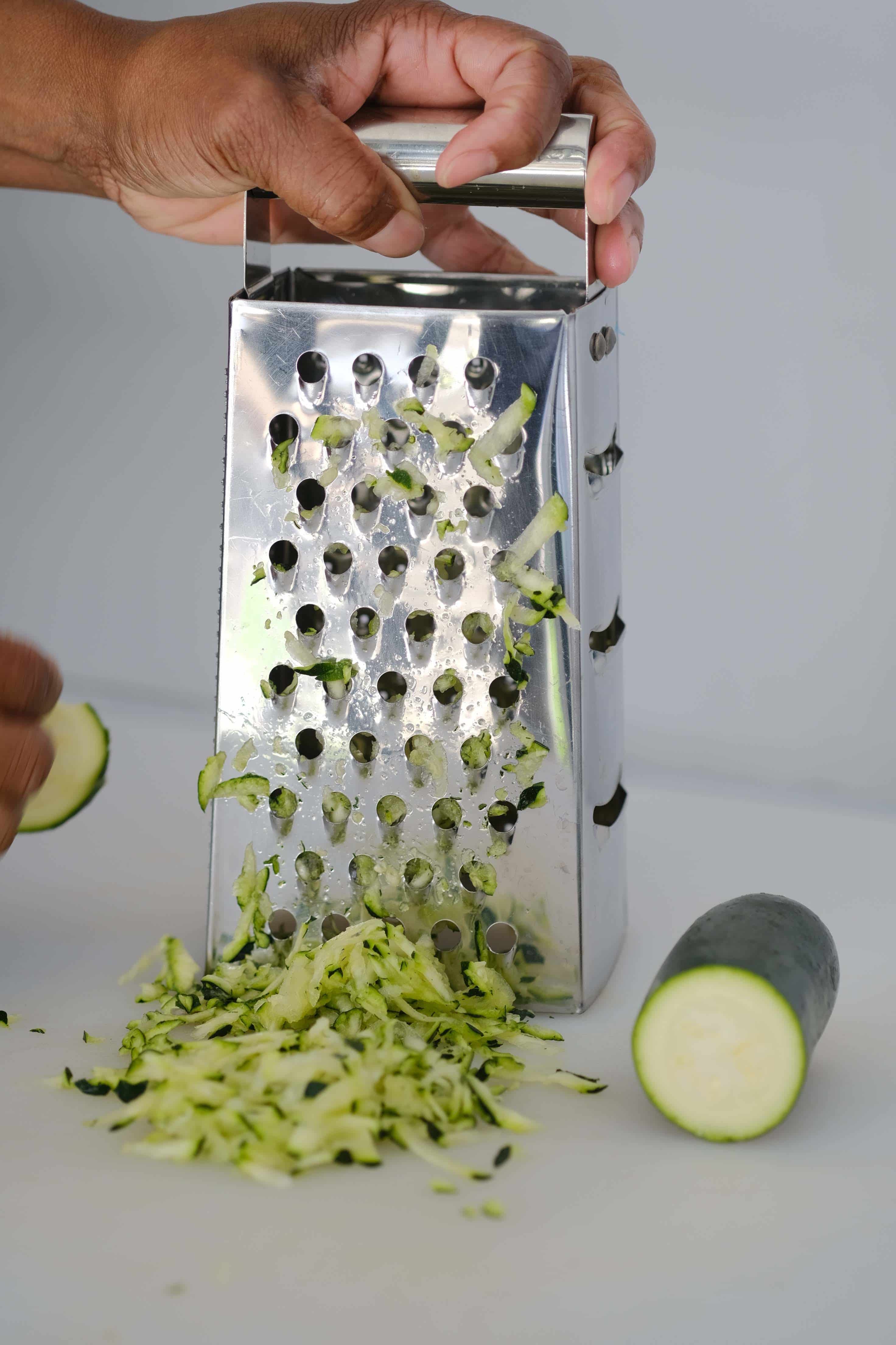 Zucchini being shredded with a food shredder