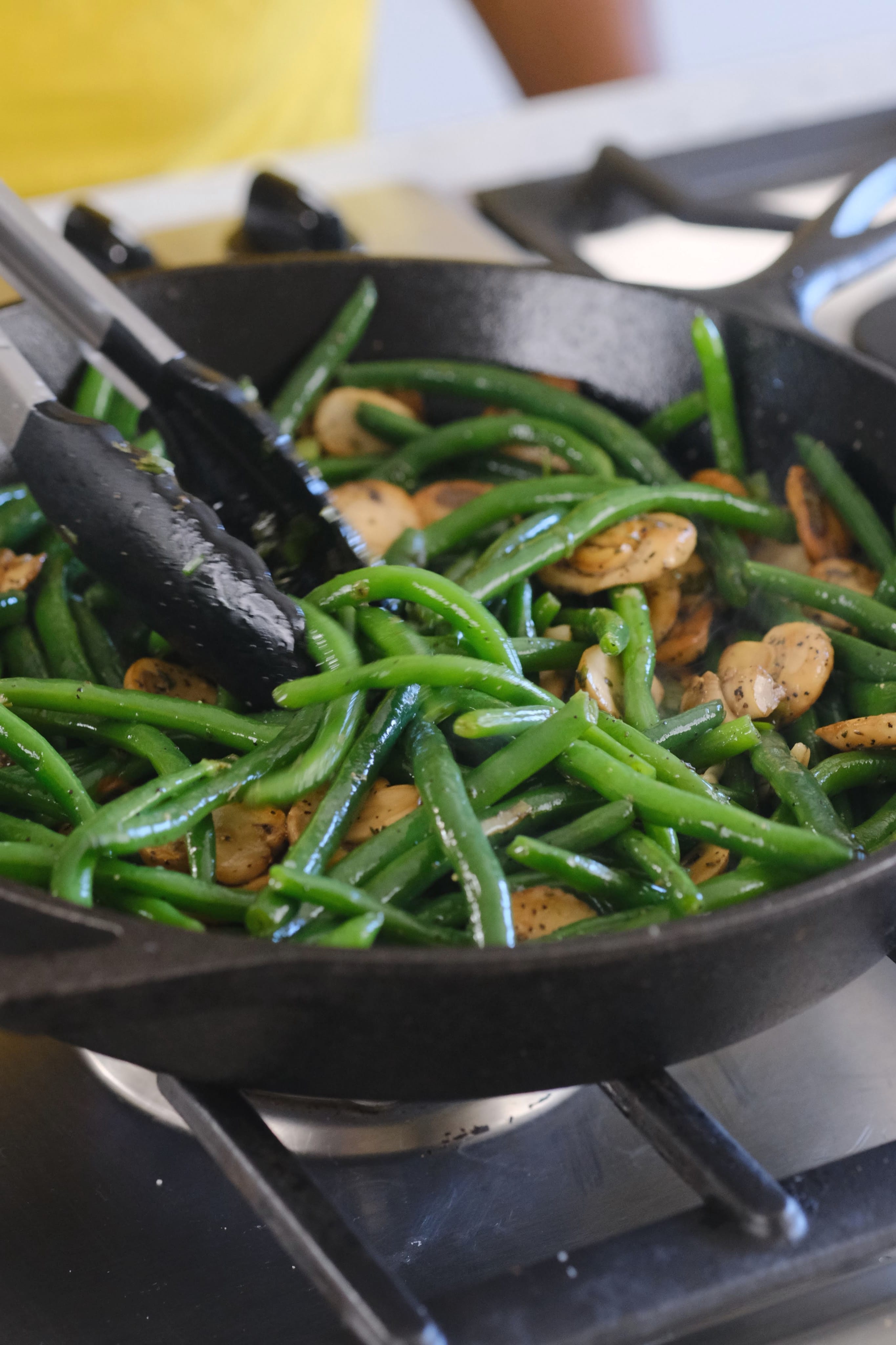 green beans and mushrooms cooking in a cast iron skillet