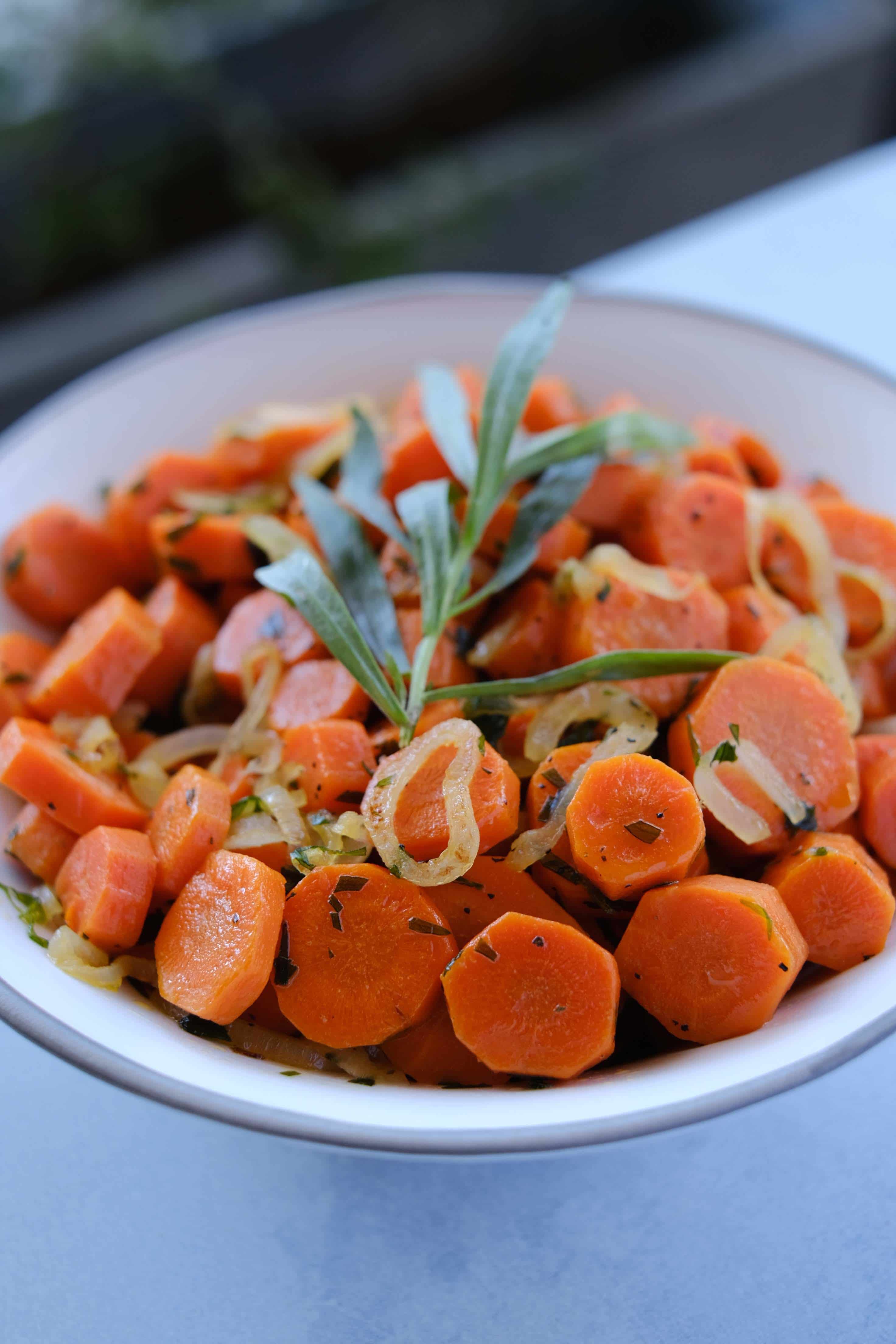 sauteed carrots tarragon and shallots in a white bowl 