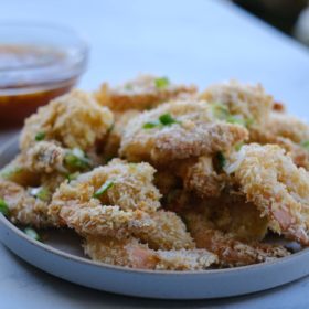 coconut shrimp on a white bowl with dipping sauce