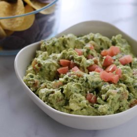 Guacamole in a white bowl and chips